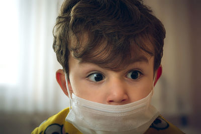 Close-up of cute boy wearing mask at home