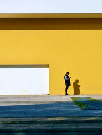 Full length of man standing against yellow wall