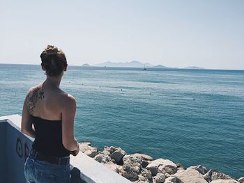 Rear view of young woman standing against sea