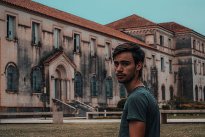 Portrait of young man standing against building