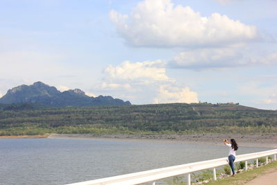 Man standing on mountain by sea against sky