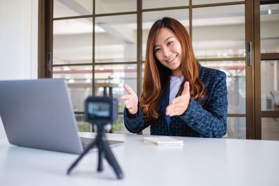 Smiling businesswoman blogging in office