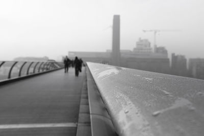 People walking on bridge in city against sky