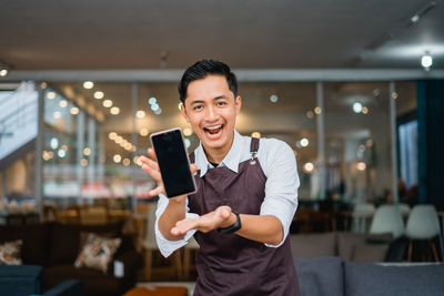 Young woman using mobile phone while standing in cafe