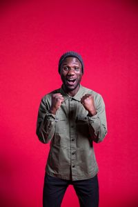 Portrait of young man standing against red background