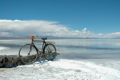 Bicycle on beach against sky