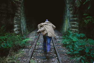 Rear view of person running towards tunnel