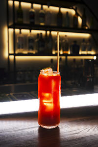 A glass of red alcohol drink with a cocktail tube on a bar counter. night club drink.