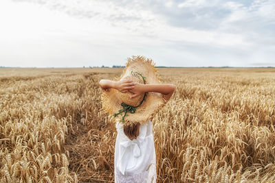 Rear view of girl standing on field against sky