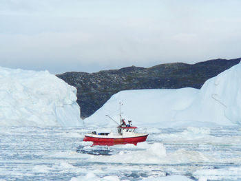 Boat on snow covered mountain against sky