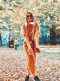 Full length of young woman standing in park during autumn