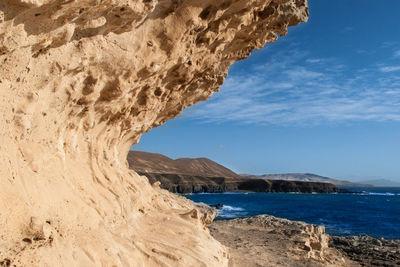 Scenic view of rock formation on beach against sky