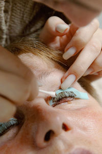 A girl cosmetologist laminates women's eyelashes.