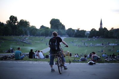 People riding bicycles on street against clear sky