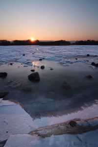 Scenic view of frozen lake against sky during sunset