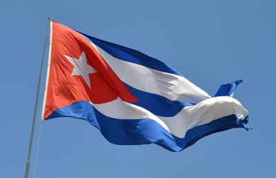 Low angle view of flag waving against clear blue sky