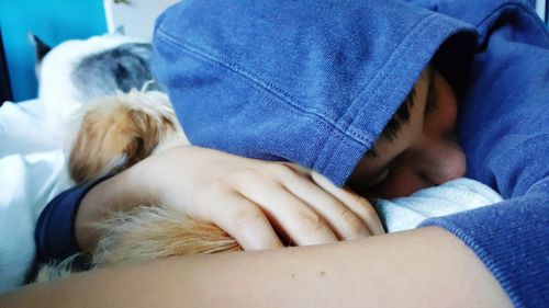 Pet owner sleeping on bed holding puppy