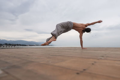 Full length of man exercising against sky