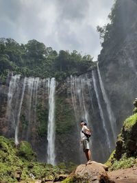 Scenic view of waterfall against rocks and mountain