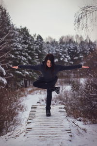 Full length of woman with arms raised in winter