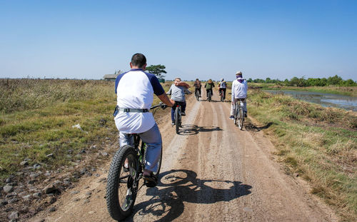 Rear view of people riding bicycle on road