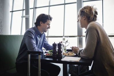 Side view of businesspeople having food at cafe in airport