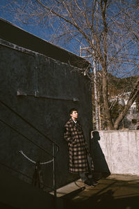 Man standing by bare tree