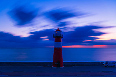 Lighthouse by sea against sky during sunset