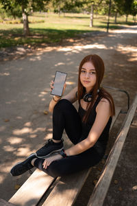 Sportive female showing smartphone sitting on bench