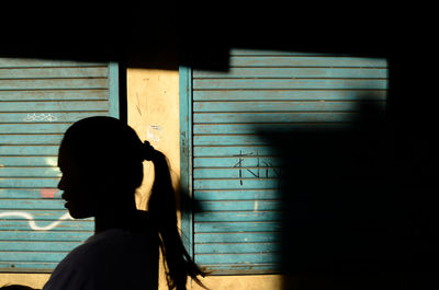 Side view of silhouette woman against window