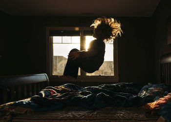 Playful boy jumping on bed at home