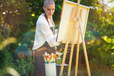 Young female artist working on her art canvas painting outdoors in her garden. art therapy.