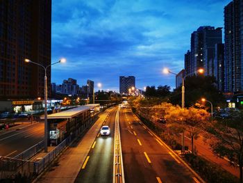 Illuminated street amidst buildings in city at night