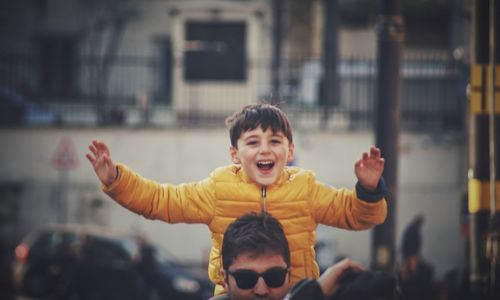Portrait of boy with arms raised in city