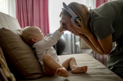 Playful mother wearing headphones playing with daughter