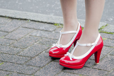 Low section of woman wearing red shoes standing outdoors
