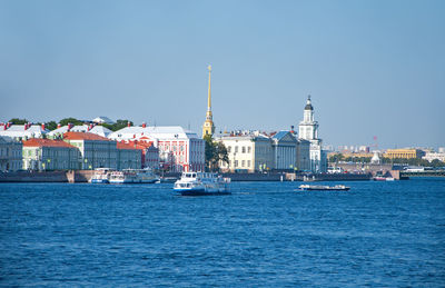 Boats in sea against clear blue sky