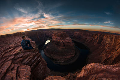 Hiker sitting on rock formation horseshoe bend