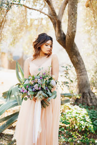 Portrait of young woman standing against plants