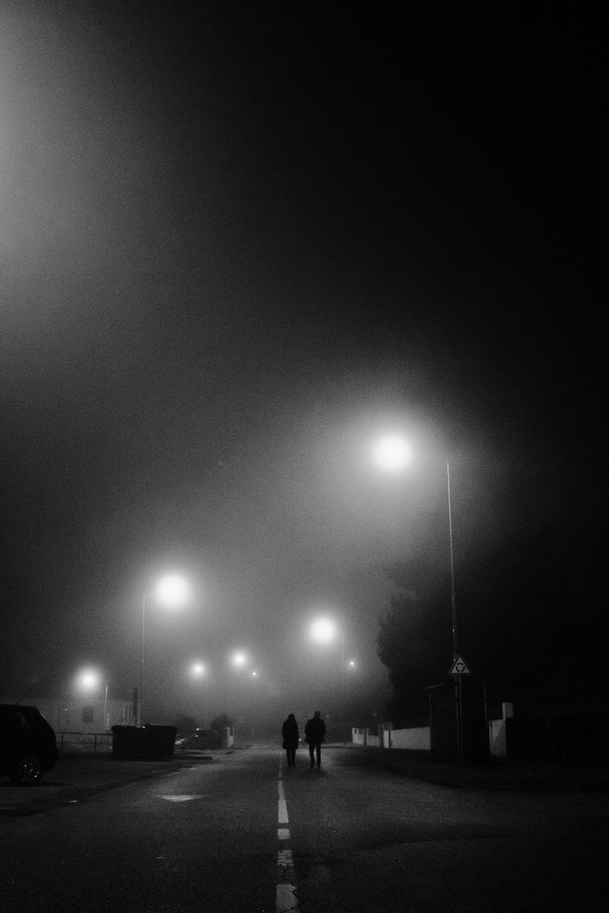 MAN ON STREET AGAINST SKY AT NIGHT