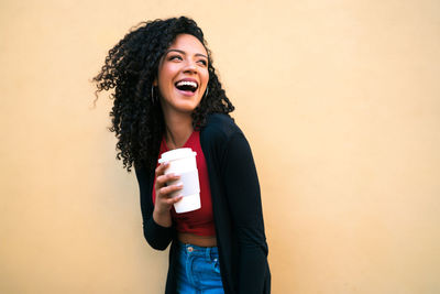 Young woman smiling while standing against wall