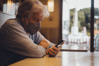 Man using mobile phone while sitting in cafe