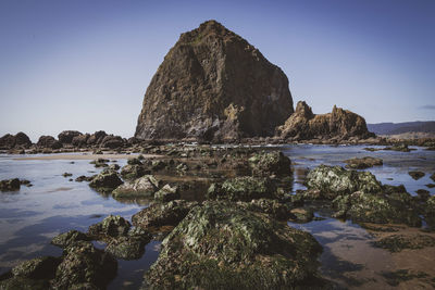 Rock formation on beach against clear sky