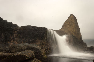 Scenic view of waterfall against sky