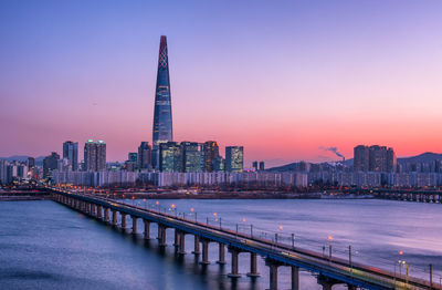 View of bridge over river and buildings against sky