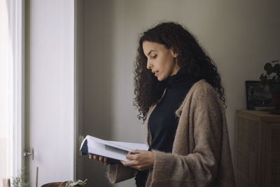 Young woman looking away while standing at home