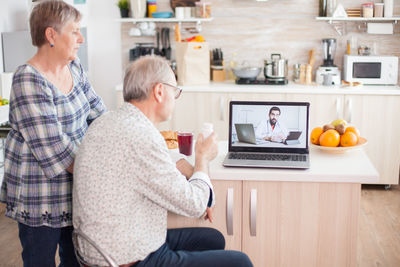 Senior couple video conferencing with doctor over laptop on table