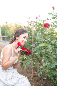 Portrait of smiling young woman holding flowers