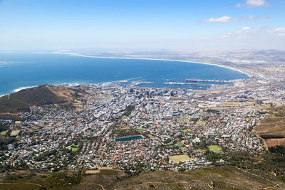 Aerial view of city by sea against sky