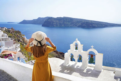 Young woman looking stunning landscape in the picturesque village of oia, santorini island, greece.